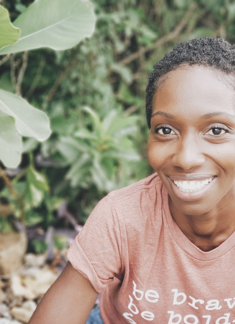 black woman smiling in front of green landscape