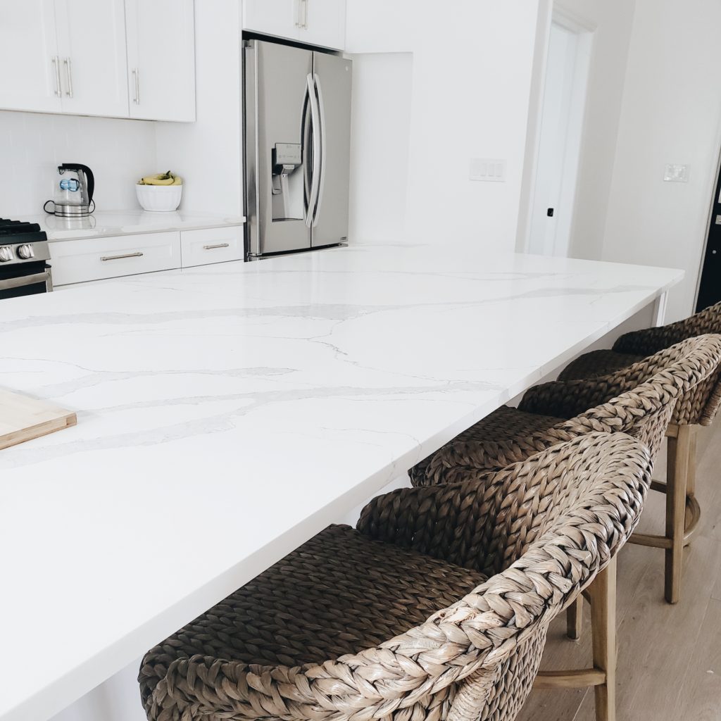 white and grey minimalist kitchen with woven counter height stools