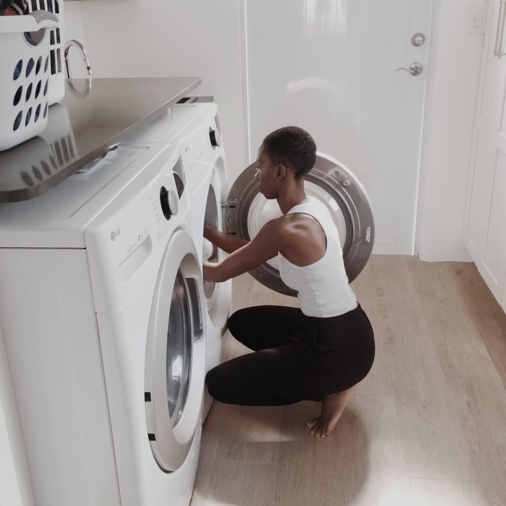 black woman putting taking laundry out of dryer